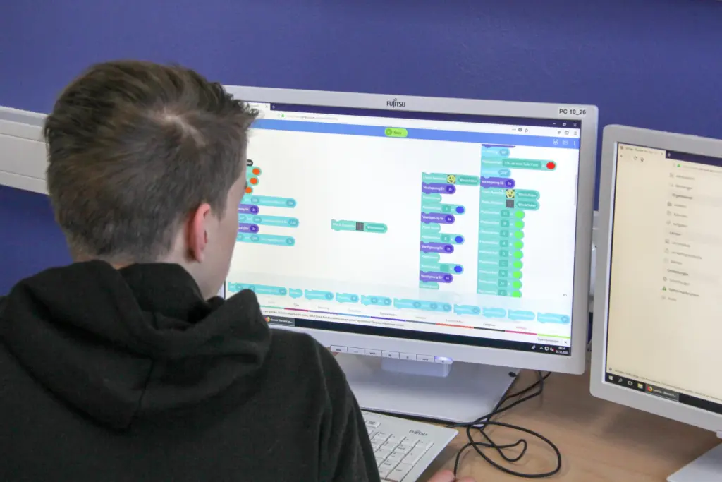 Schüler programmiert mit einem Blockly-Diagramm im Informatikunterricht