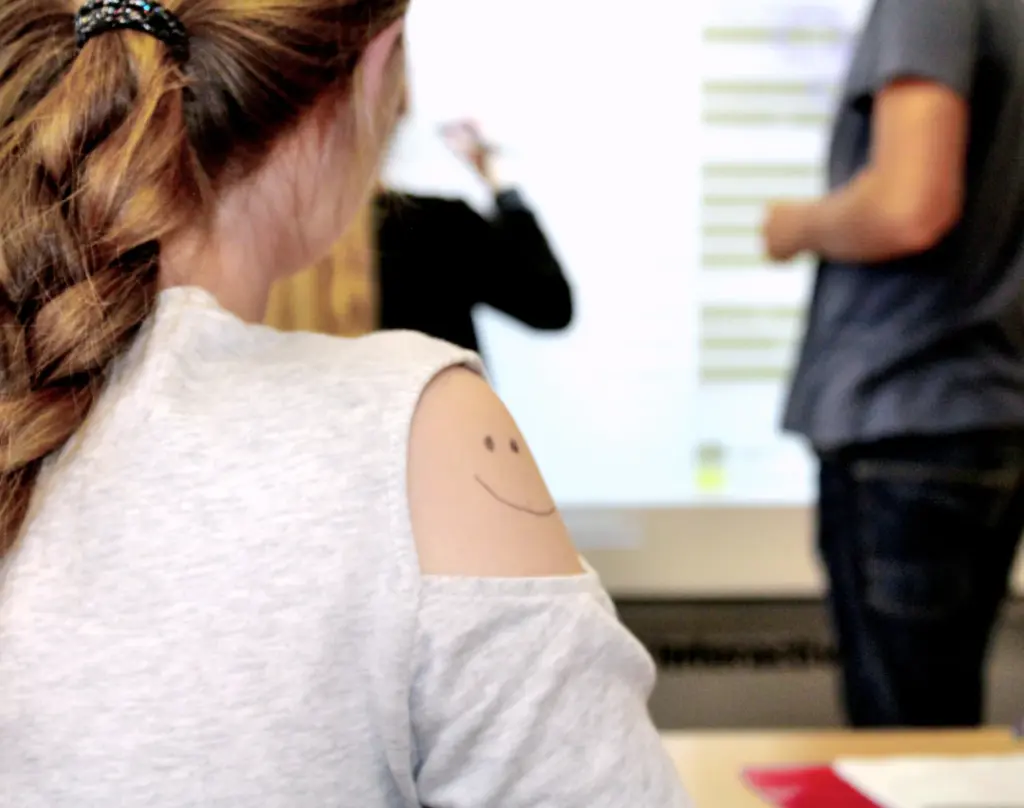 Schüler mit einem aufgemalten Smiley-Gesicht auf dem Arm