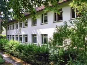 Weißes Schulgebäude mit Efeufassade und Garten